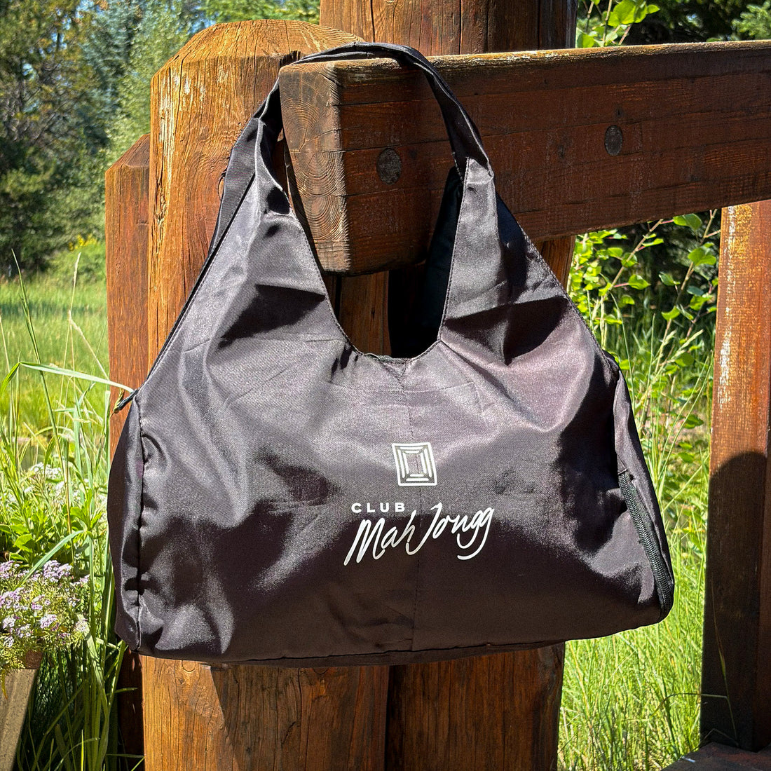 A black nylon tote bag with white printed branding reading &