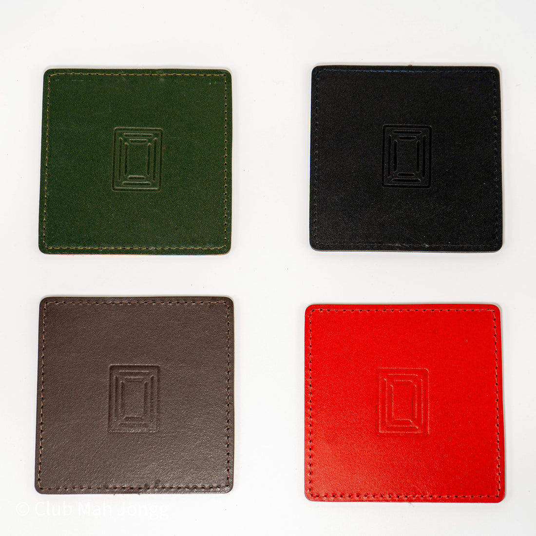 Four square leather mahjong coasters in green, black, brown and red