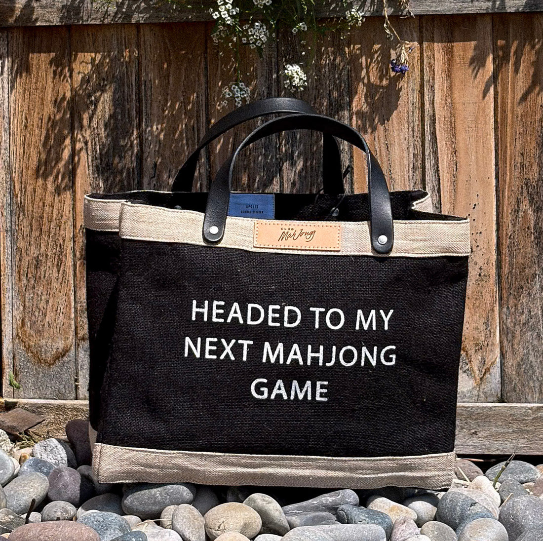 Club Mah Jongg black jute tote bag with beige trim and black leather handles, with a Club Mah Jongg patch and the white text &